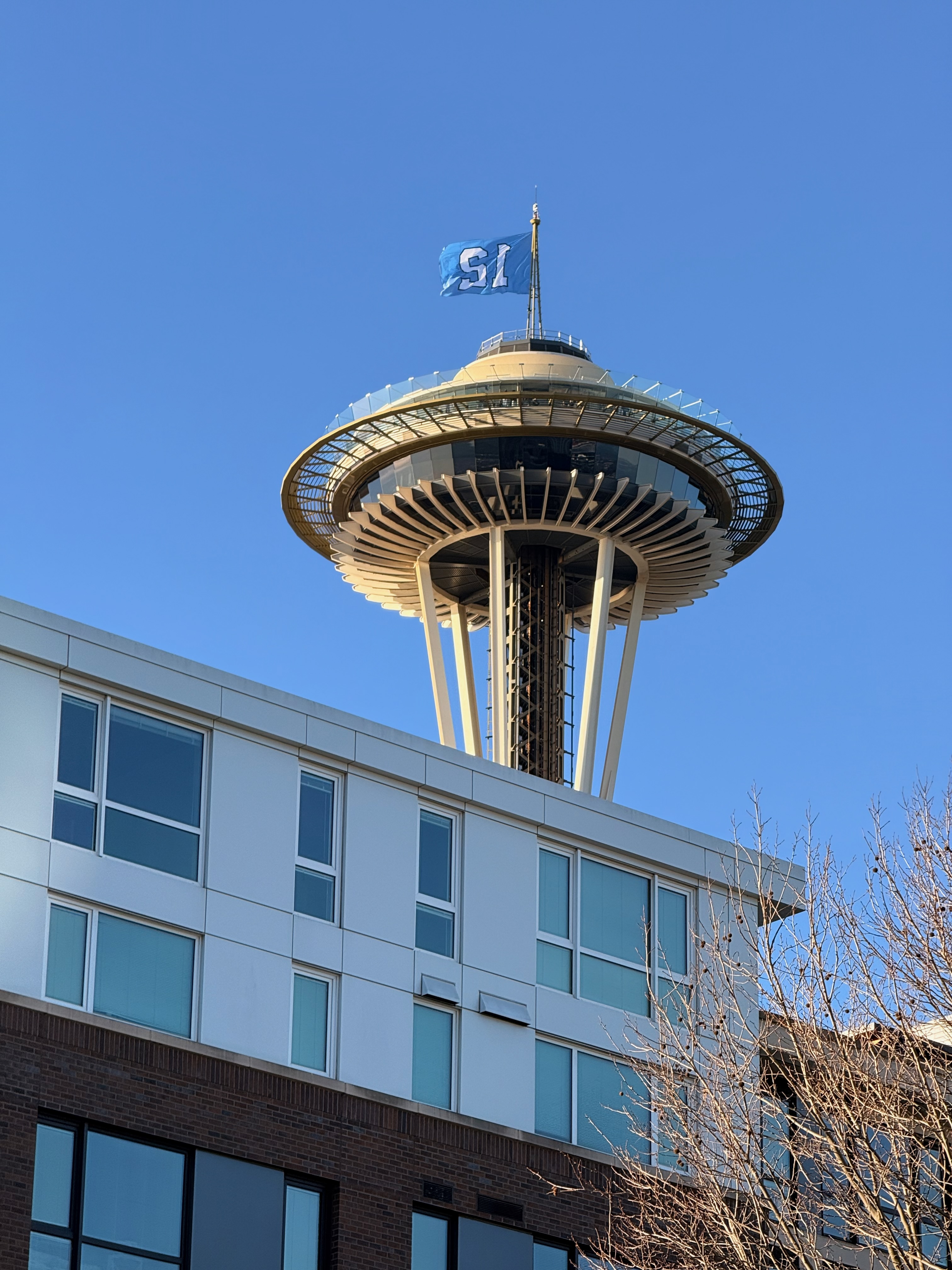 The 12 flag flying at the top of the Space Needle against a clear blue sky