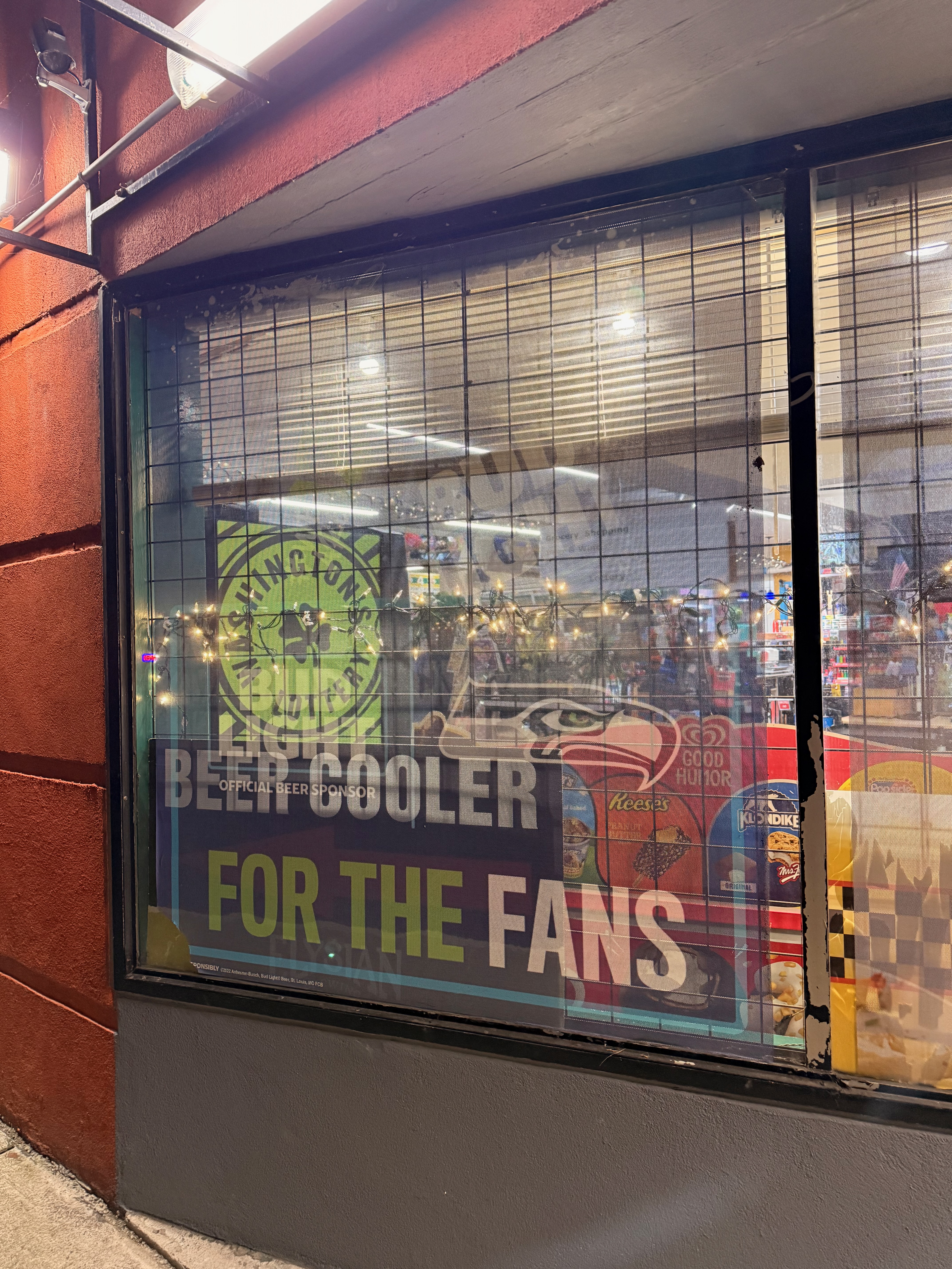 A store window with Seahawks branding and a Beer Cooler For The Fans sign at night