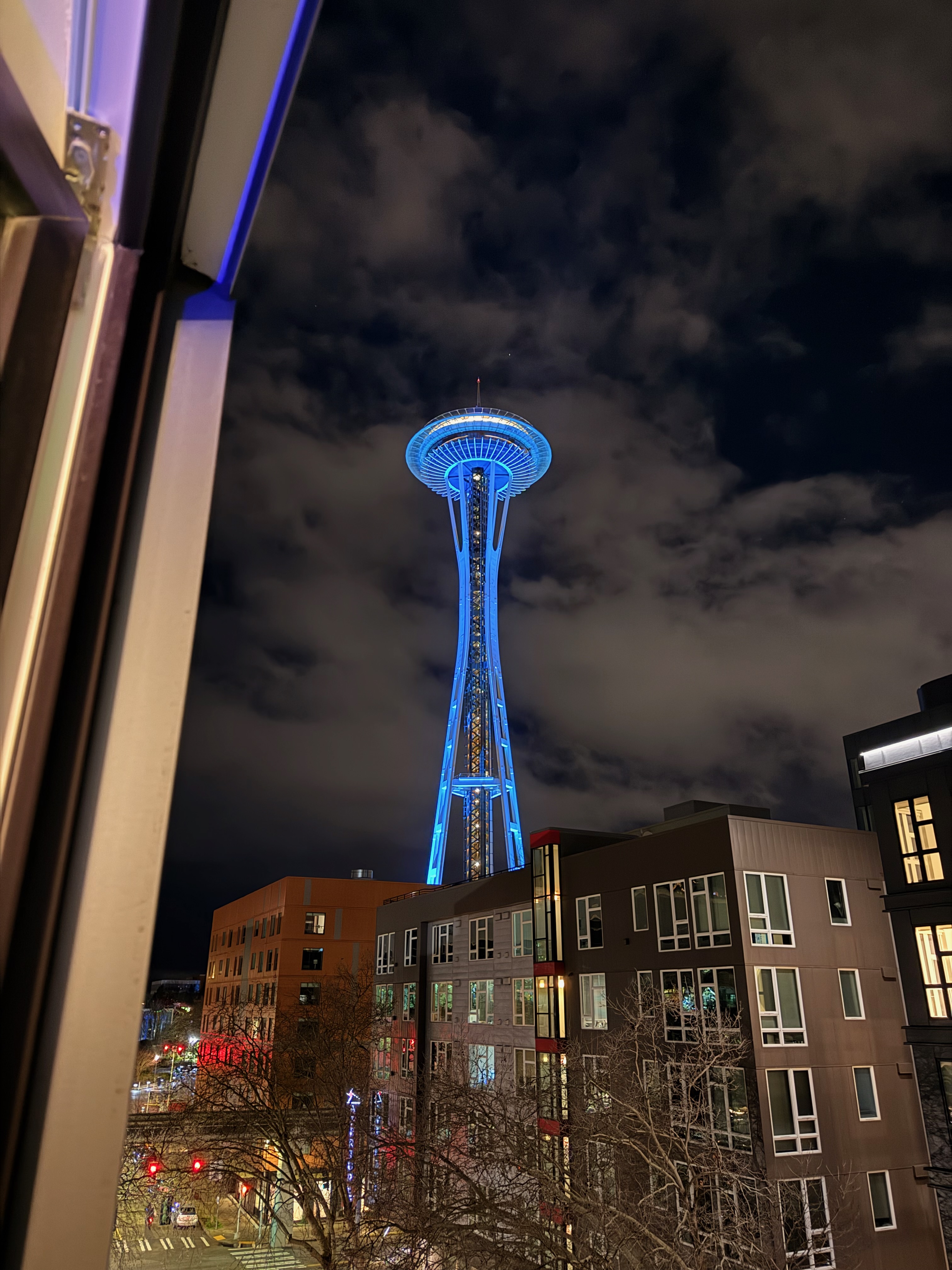 The Space Needle lit up in bright blue against the night sky