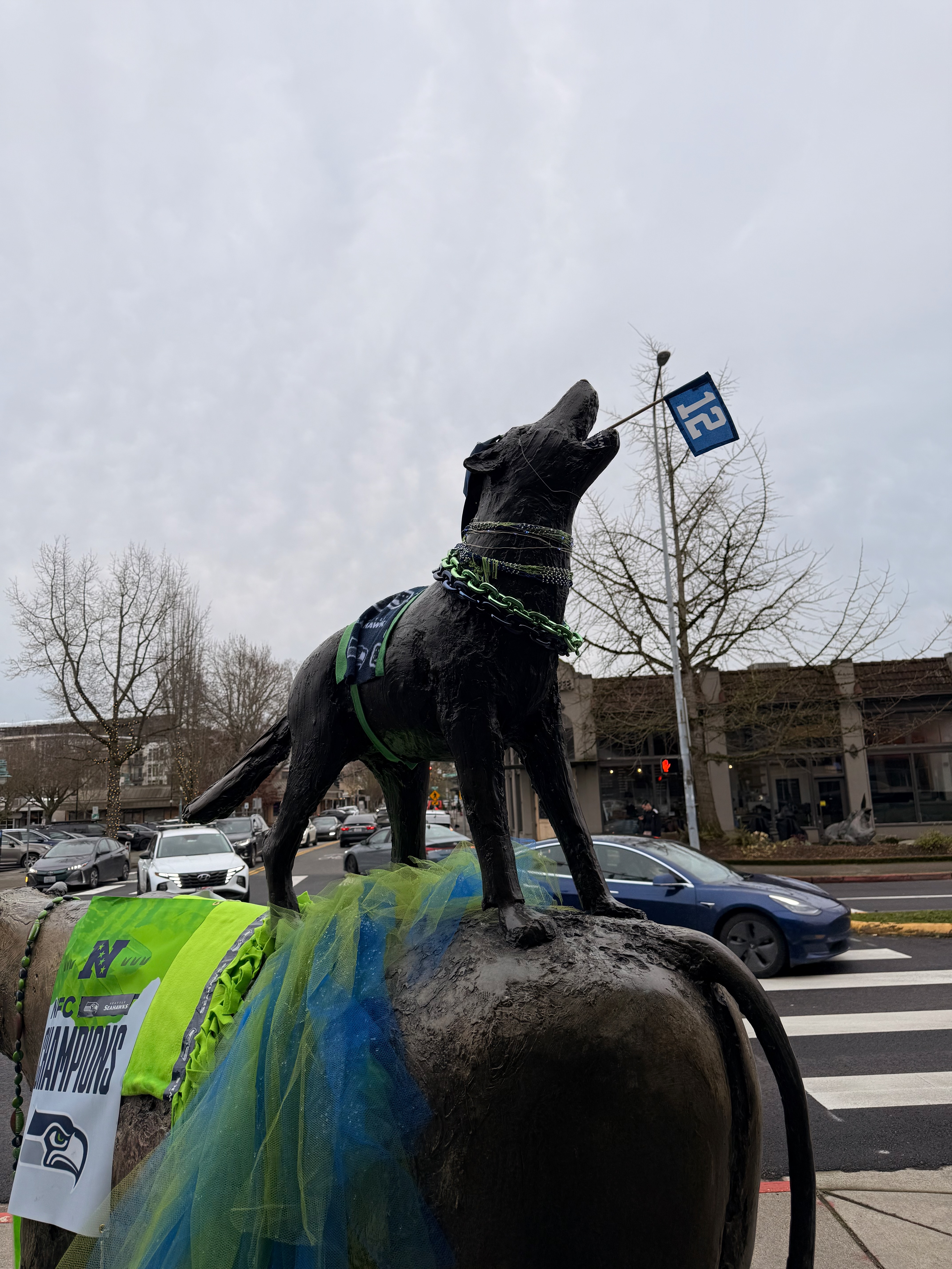 A dog statue decorated with Seahawks gear, a 12 flag, and a Champions sign